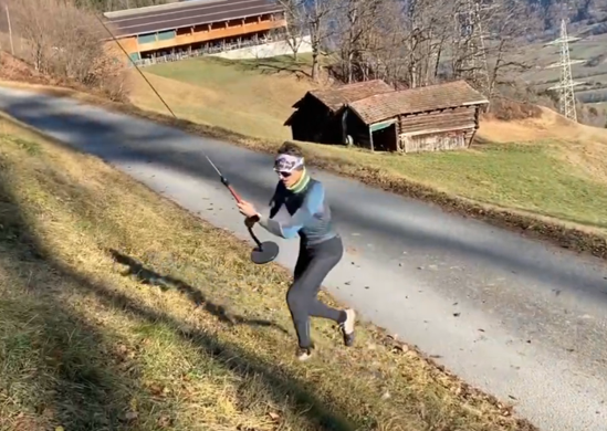 Läuferin mit Teller und Skistöcken am Hang